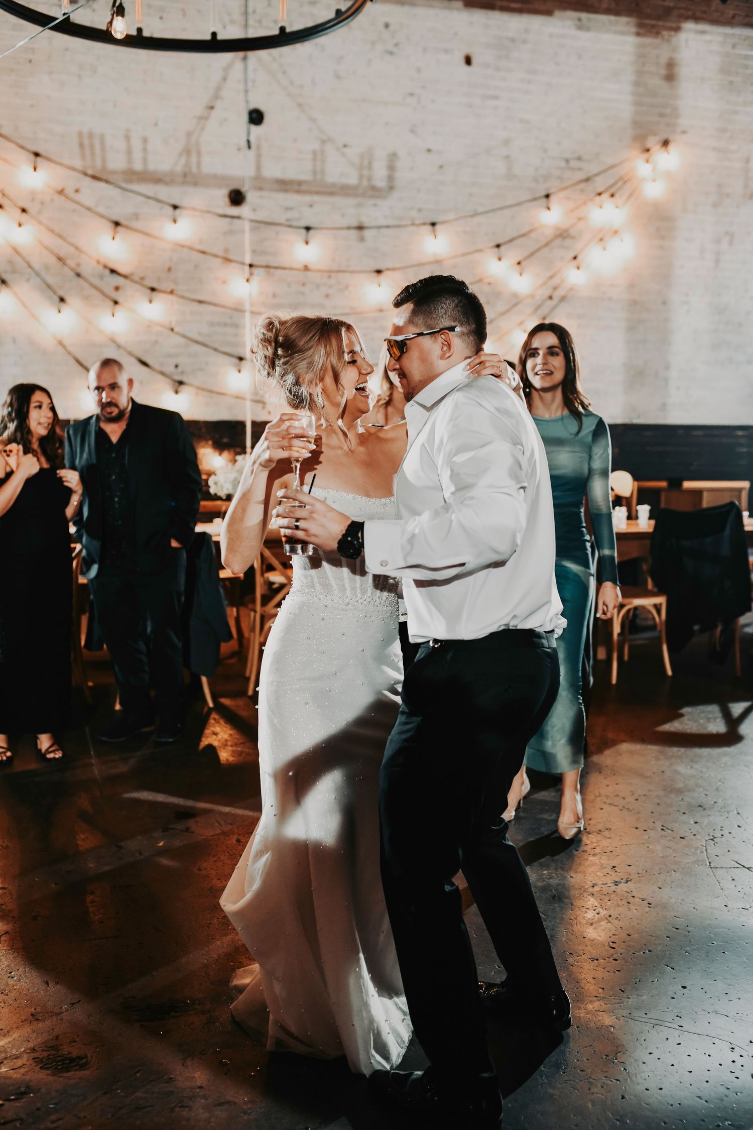 Couple slow dancing with tear-filled smiles during their intimate wedding moment.