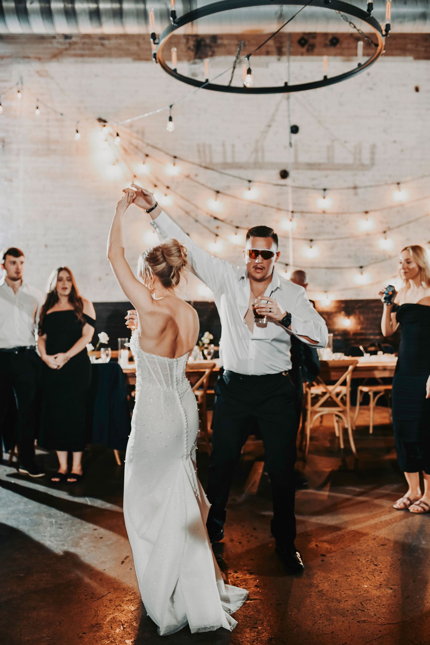 Romantic first dance moment with the couple swaying under warm industrial lights.