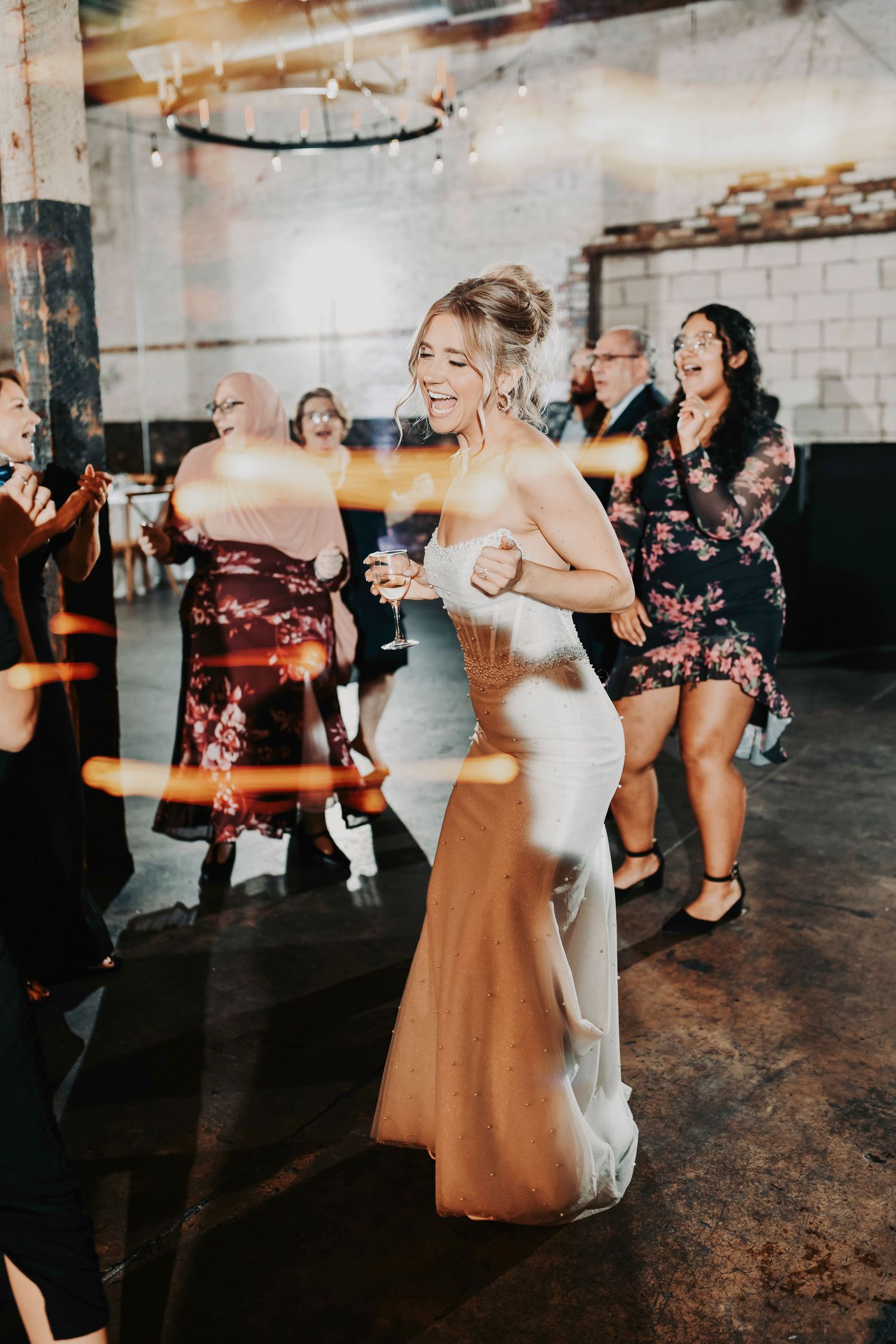 High-energy dance moment with the couple laughing under modern reception lighting.