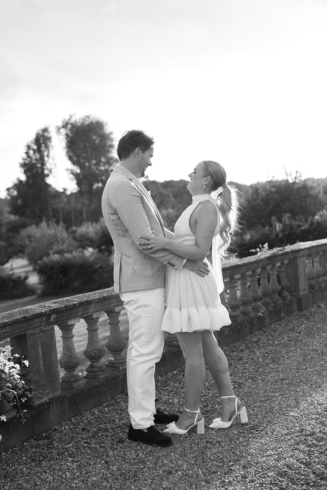 Wedding guests enjoy conversation and drinks at outdoor reception tables during golden hour.