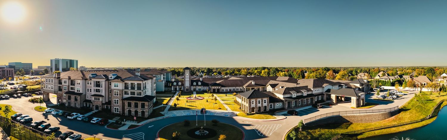 Panoramic aerial view of a suburban neighborhood with modern homes and buildings against a clear blue sky.