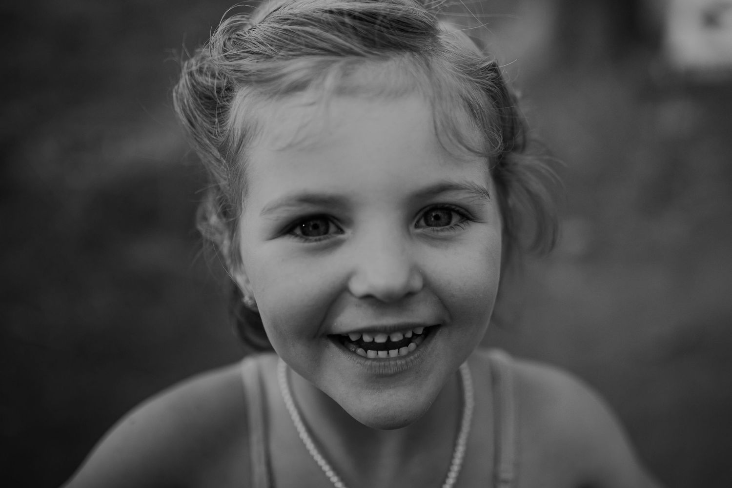 A black and white photo series showing close-up portraits of a young child's face with different joyful expressions.