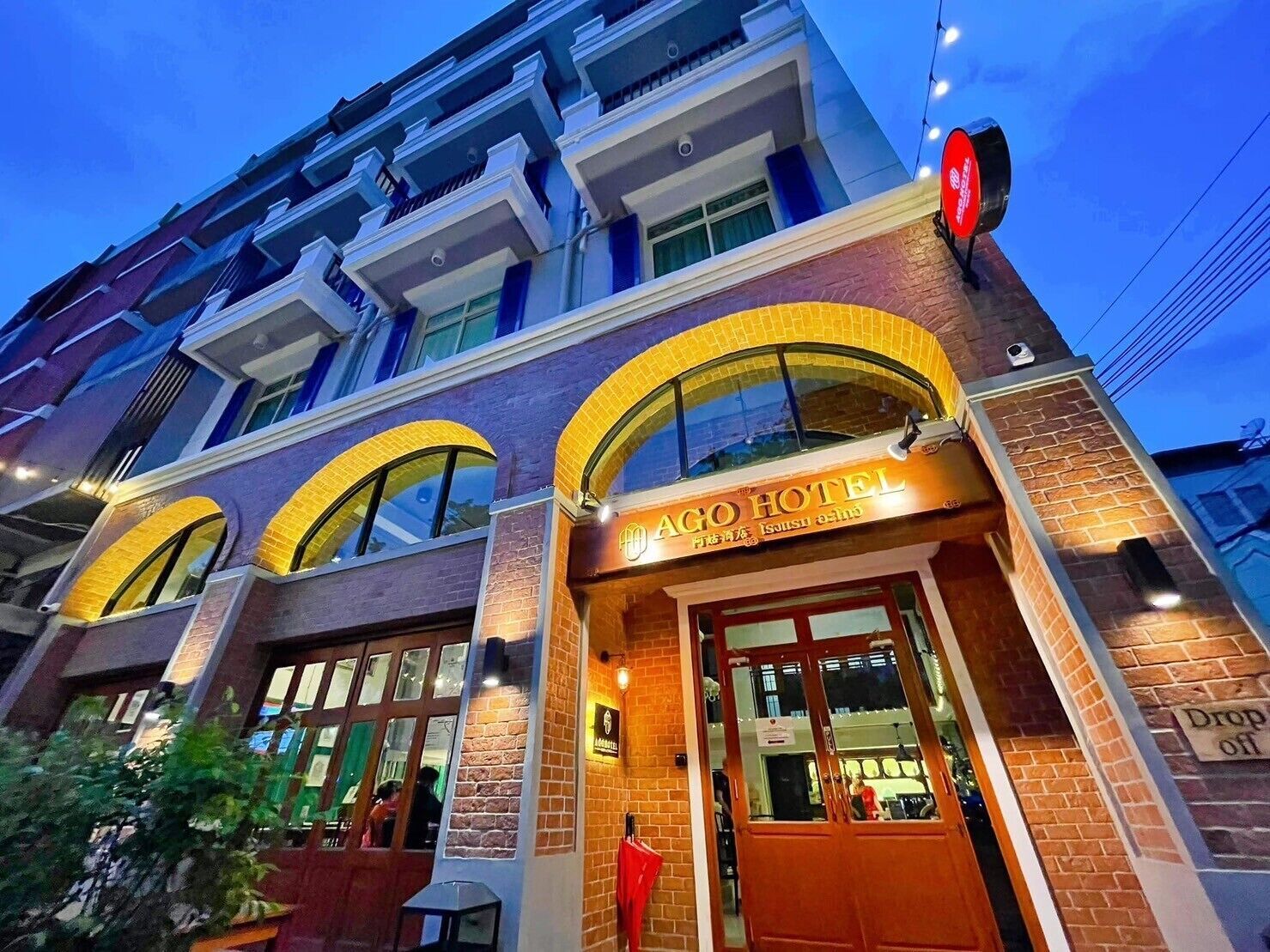 Low angle view of modern apartment buildings with illuminated storefronts and yellow awnings at dusk.