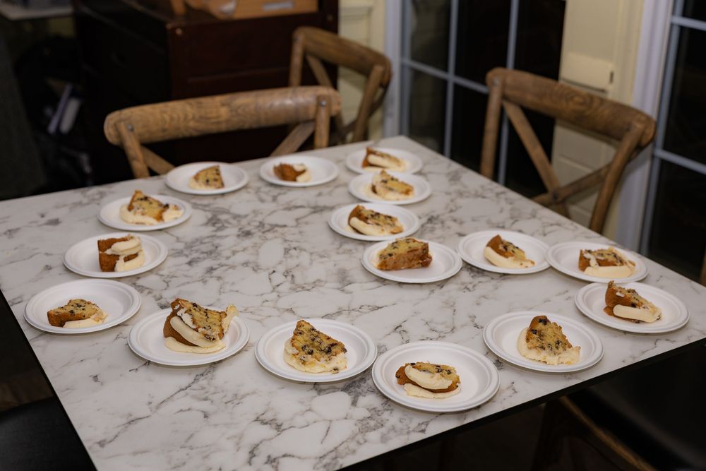 Multiple white plates with slices of cake or pie arranged on a marble table for a tasting event.
