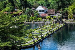 Aerial view of Tirta Gangga water palace in Bali with ornate fountains, lush gardens, and serene blue water.