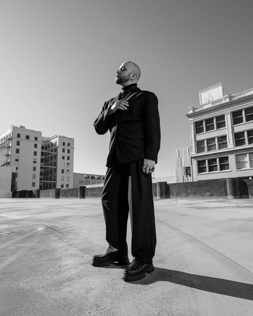 A series of black and white photos showing a person walking along an empty urban plaza with buildings in the background.