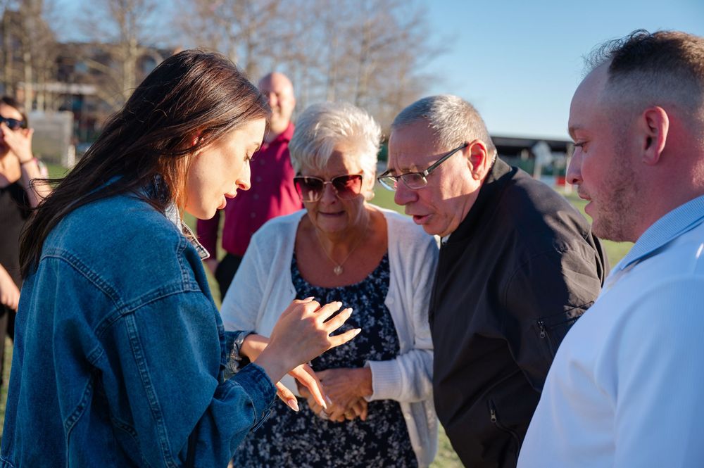Group of four people engaged in conversation outdoors on a sunny day in a park setting.