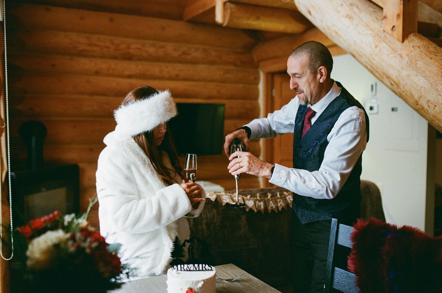 35 mm film photo of groom pouring champagne in a log cabin in Revelstoke, BC