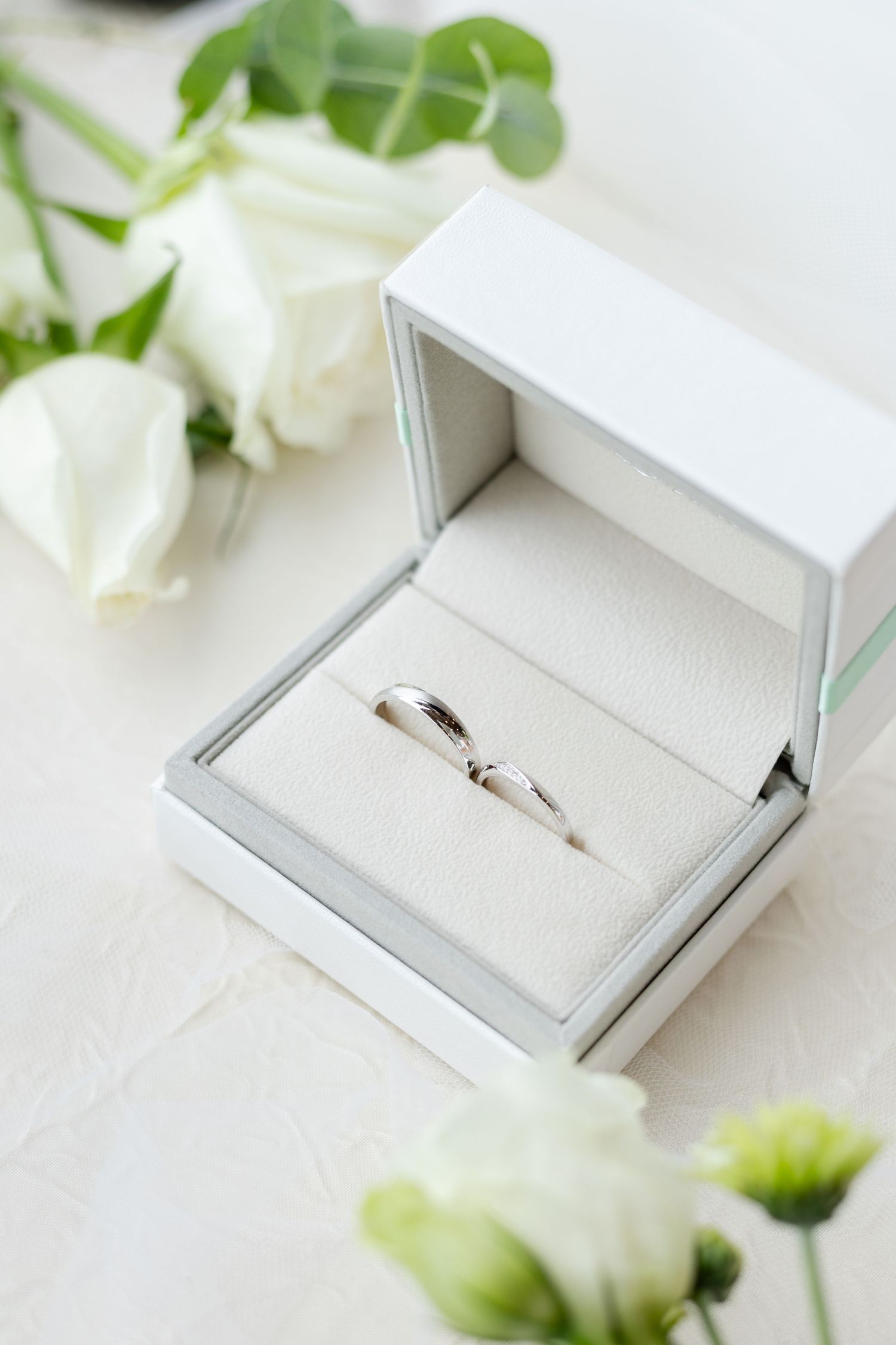 wedding photographer in singapore. bridal details, wedding ring in luxurious grey satin ring holder and white roses. bright airy photographs