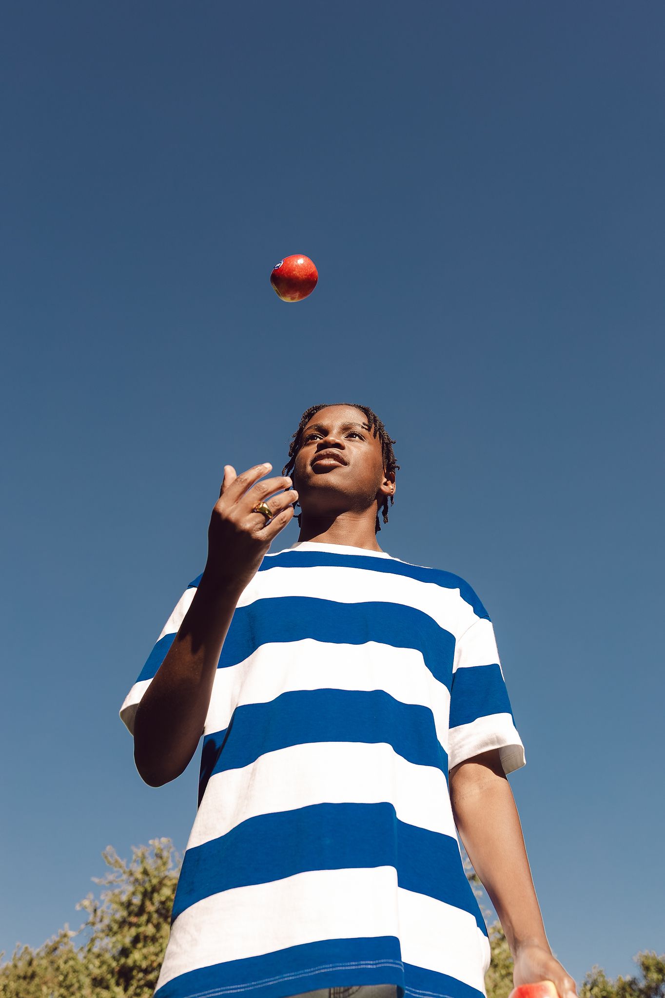Young man throwing a Jazz apple up in the air