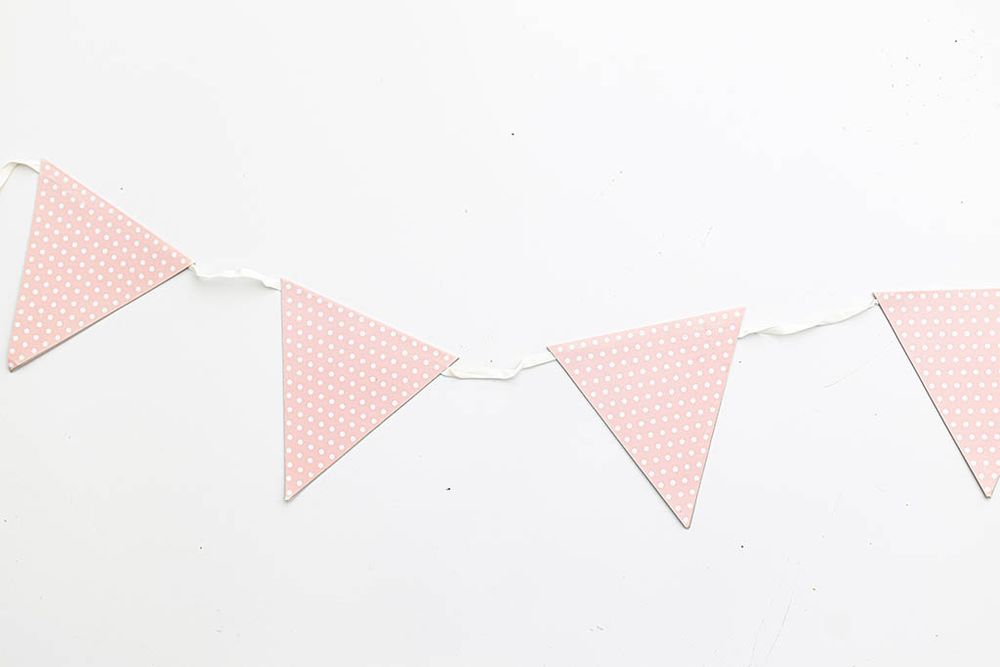 Pink polka dot triangle pennant flag bunting garland on white background.