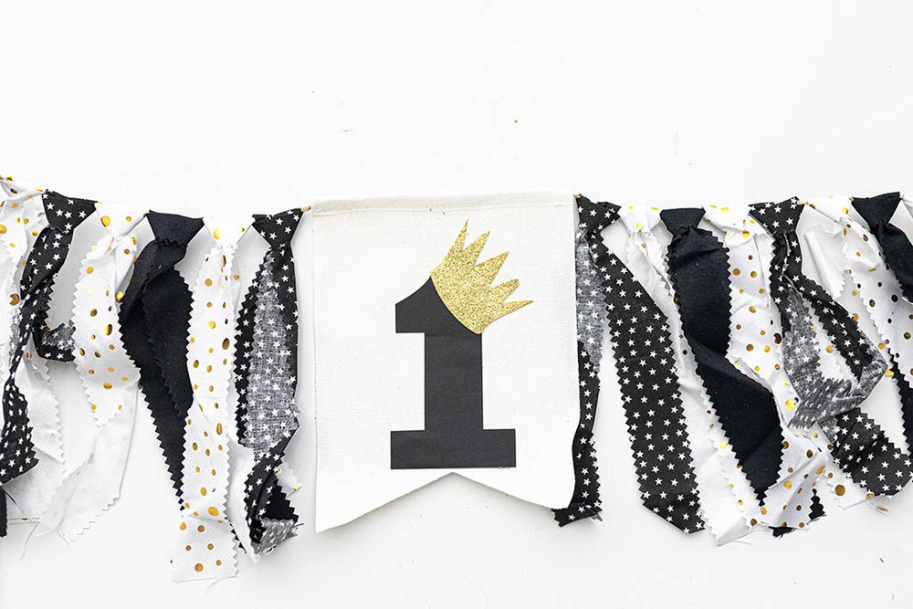 Black and white polka dot first birthday high chair banner with gold glitter crown.