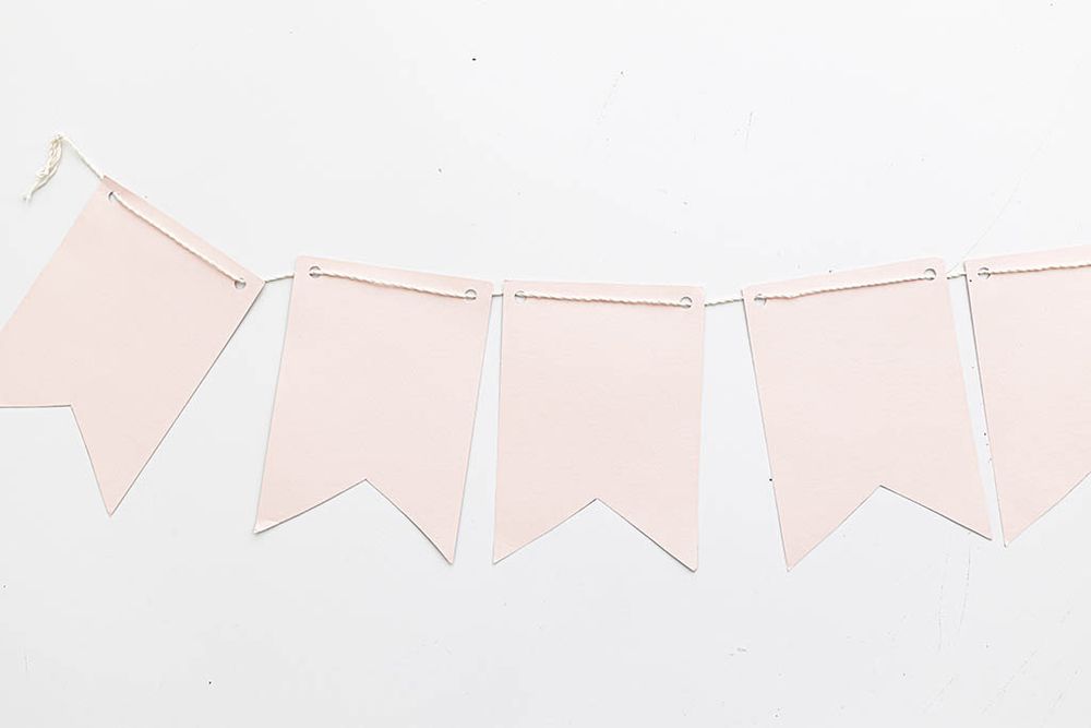 Blush pink plain pennant flag bunting banner garland on white background.