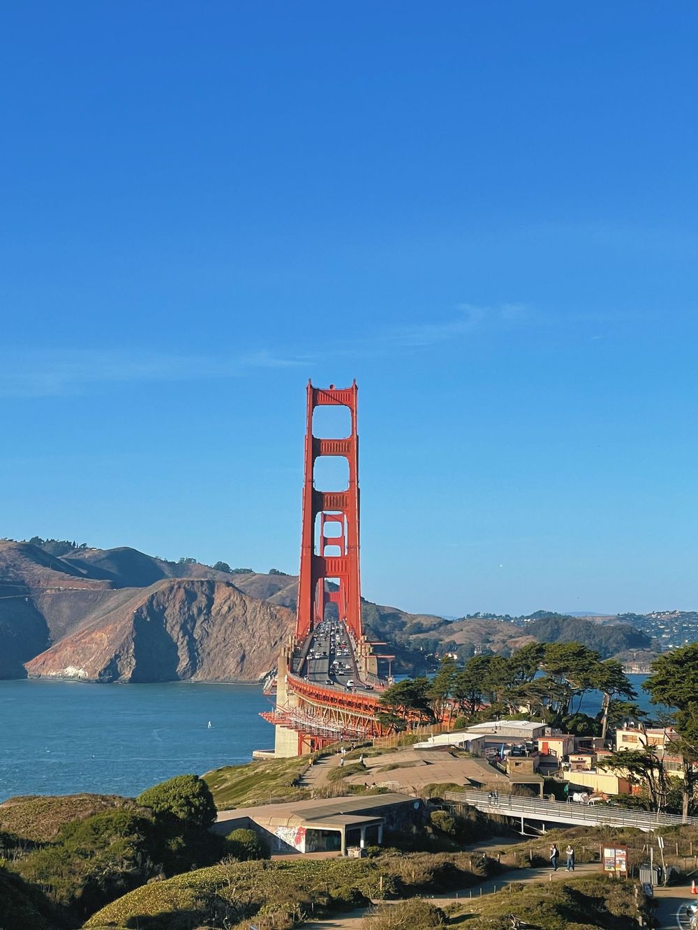 Iconic Golden Gate Bridge tower against a bright blue sky with San Francisco Bay views.