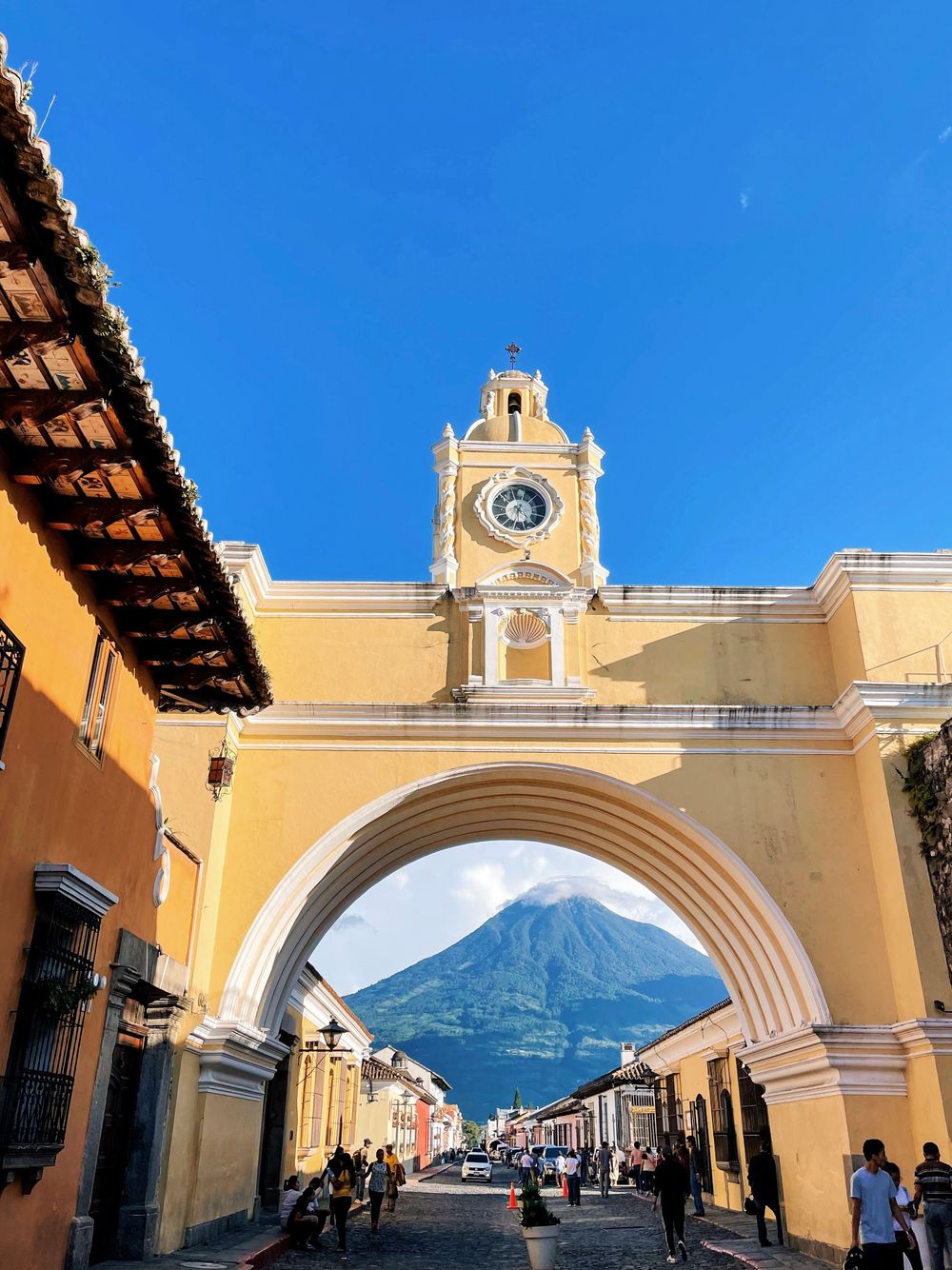 Santa Catalina Arch in Antigua Guatemala with a volcano visible through the yellow archway.