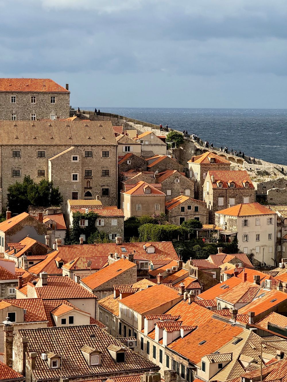 Aerial view of Dubrovnik old town with orange terracotta rooftops and historic stone buildings overlooking the Adriatic Sea.