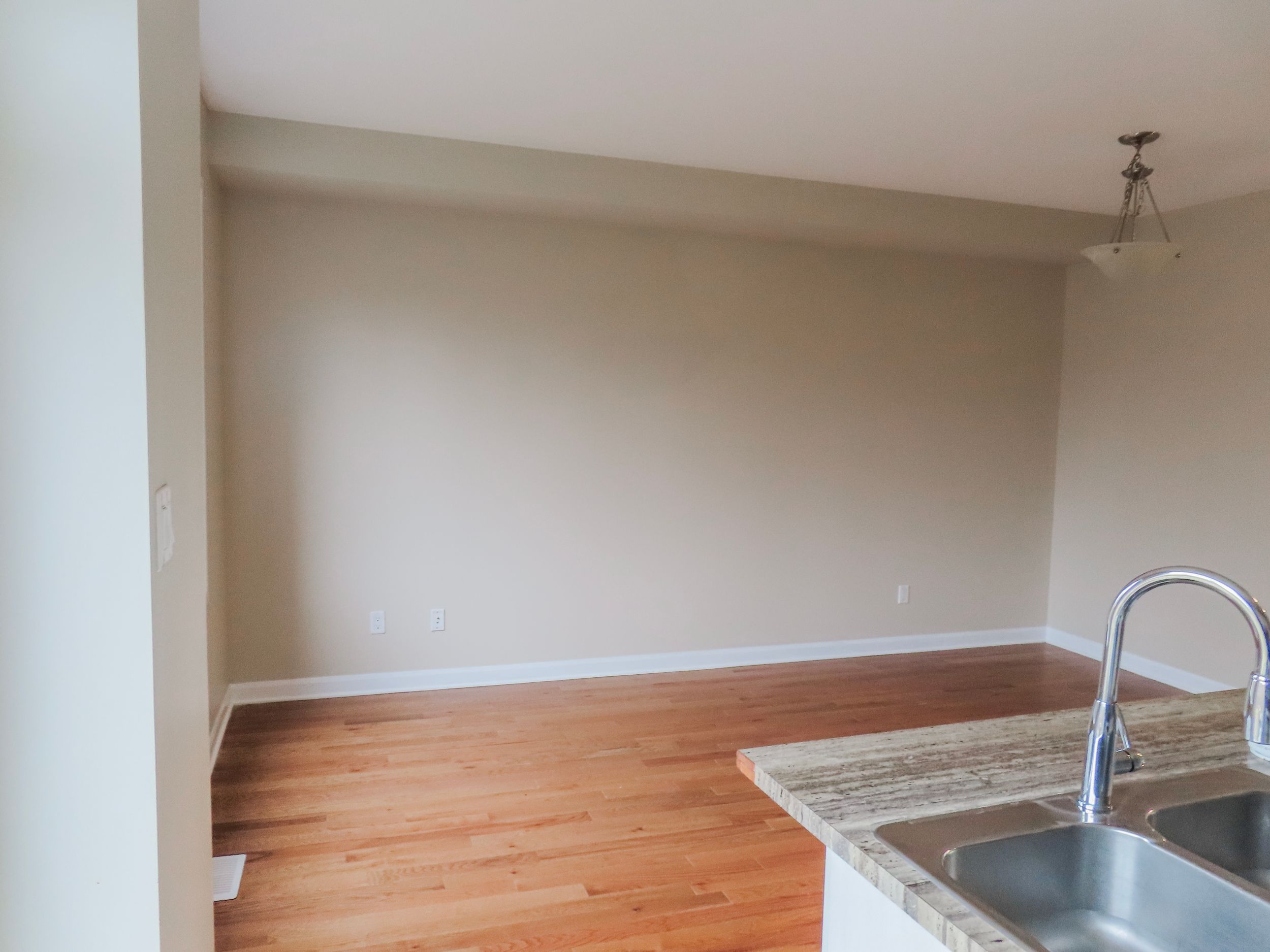 Open dining area with hardwood floors, neutral beige walls, and pendant light fixture.
