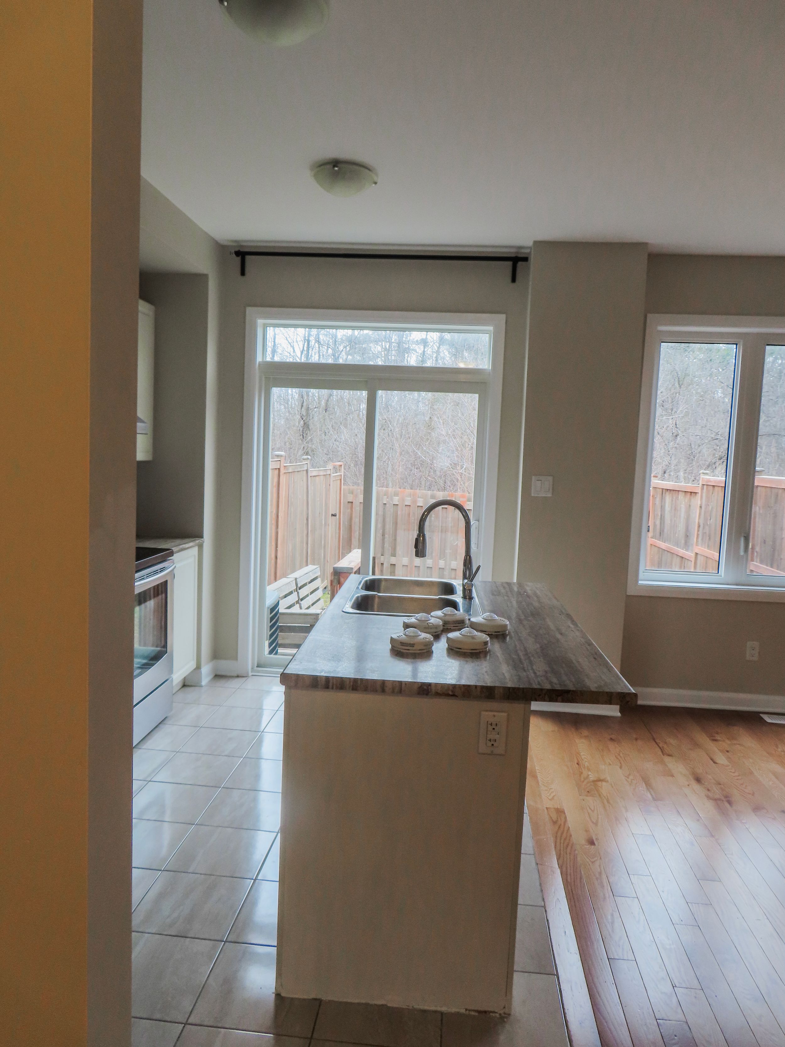 Modern kitchen island with black faucet, butcher block countertop, and large windows overlooking a wooden deck.