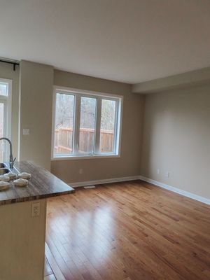 Bright open living area with hardwood floors, large window, and butcher block kitchen counter.