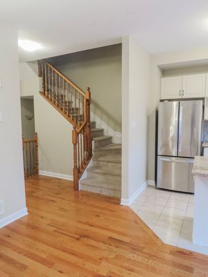 Open concept home interior featuring hardwood floors, wooden staircase, and stainless steel refrigerator.