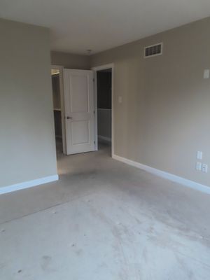 Empty bedroom with beige carpet, neutral walls, white baseboards, and an open door leading to a hallway.
