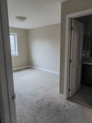 Vacant bedroom featuring light beige carpet, neutral painted walls, white trim, and a window with natural light.
