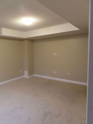 Empty room with beige walls, white baseboards, and light carpet featuring a recessed ceiling with built-in lighting.