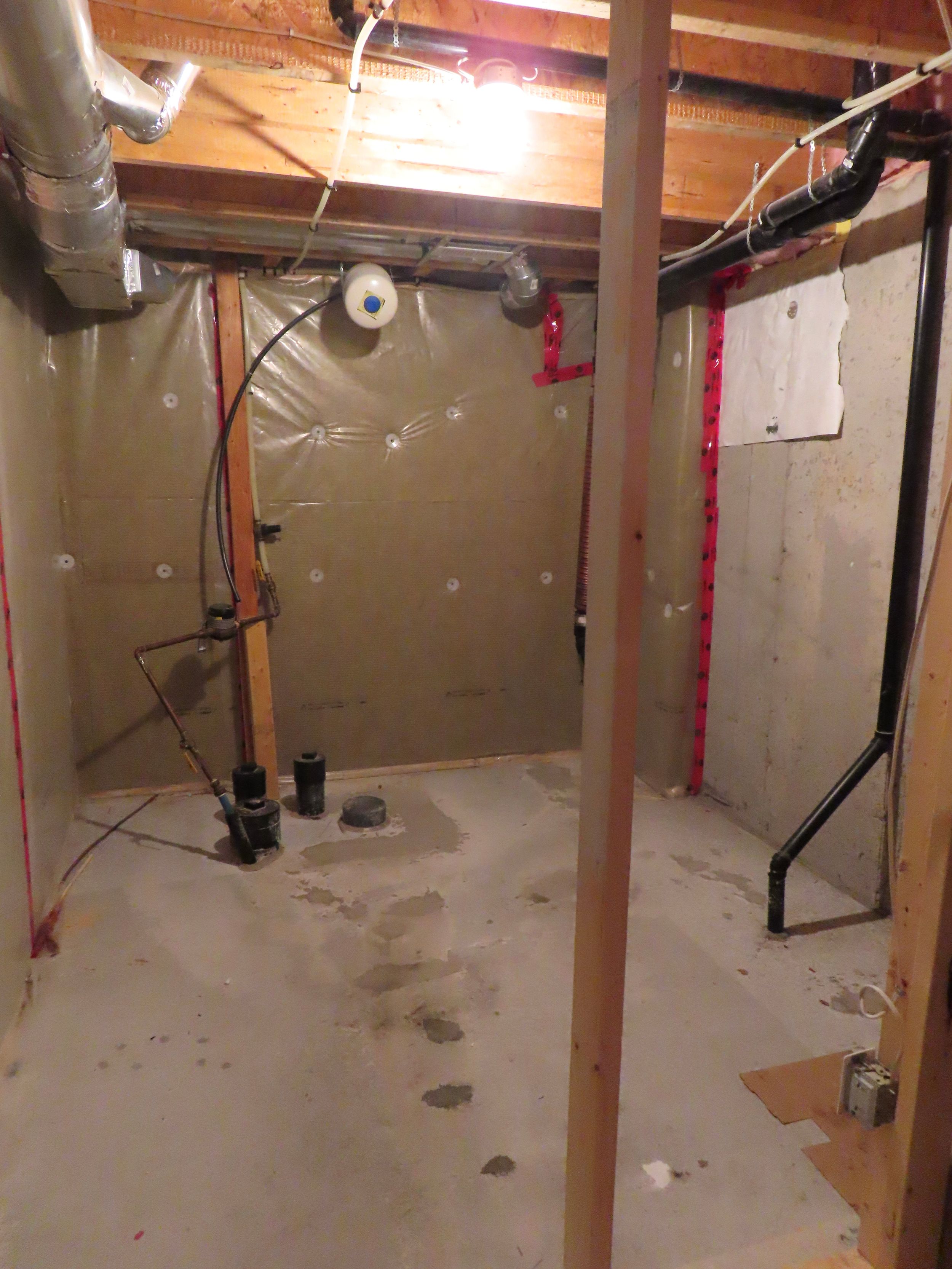 Unfinished basement utility room with sump pump, exposed pipes, and vapor barrier wall insulation.
