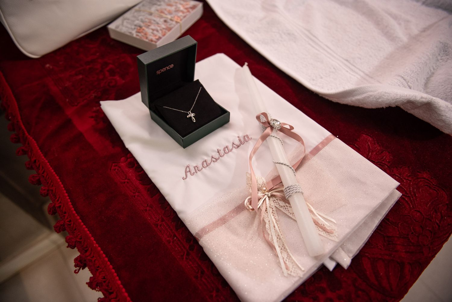 Christening keepsakes including cross necklace jewelry box and embroidered Anastasia baptism cloth.