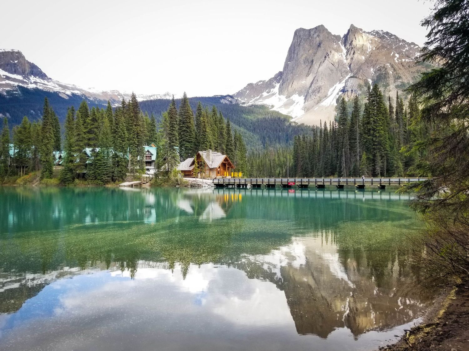 Emerald Lake Lodge reflects in pristine turquoise waters with snow-capped mountains in the Canadian Rockies.