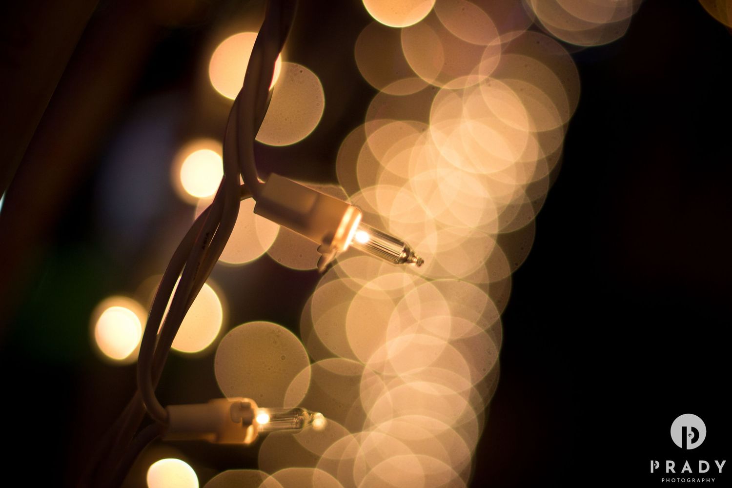Artistic bokeh photography of string lights creating soft glowing circles against dark background.