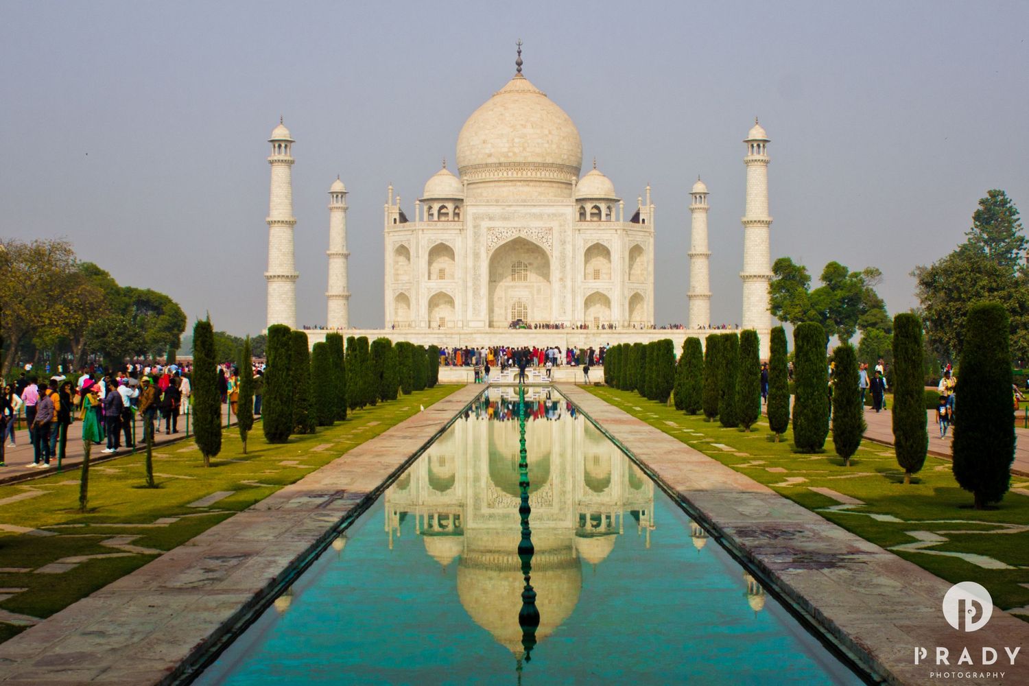 Symmetrical view of the Taj Mahal with its white domes and minarets reflecting in a tranquil pool.