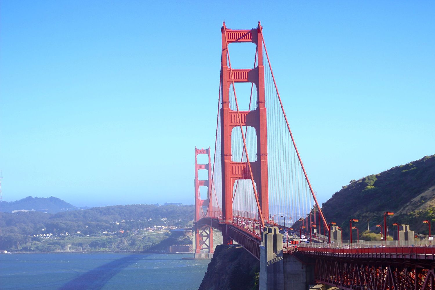 Iconic red Golden Gate Bridge spanning across San Francisco Bay under clear blue skies.
