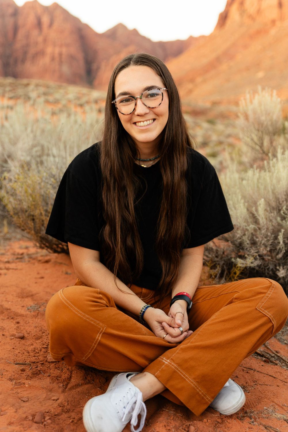 a woman sitting cross legged in the red mountains of Ivins Utah