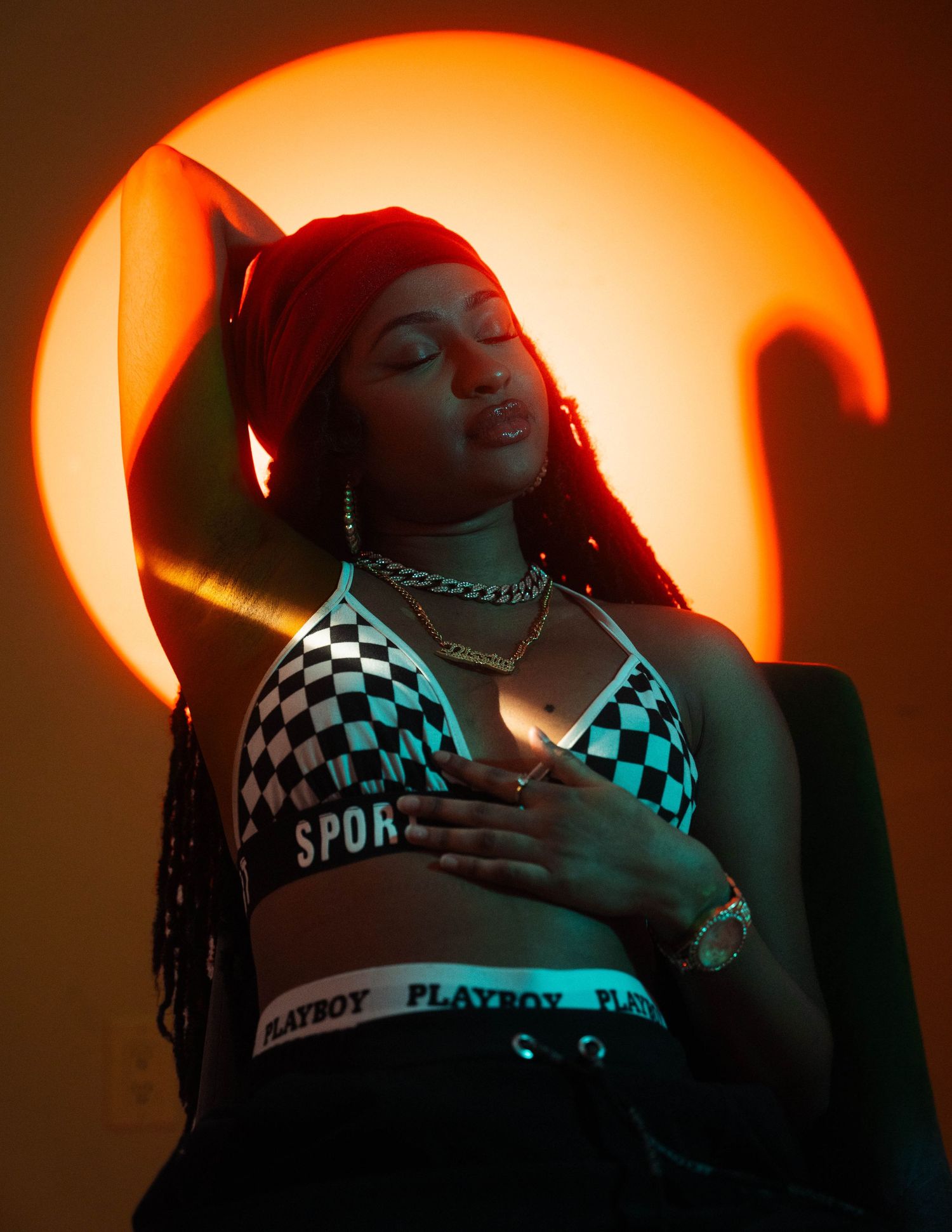 Fashion portrait with checkered top against orange sunset backdrop.