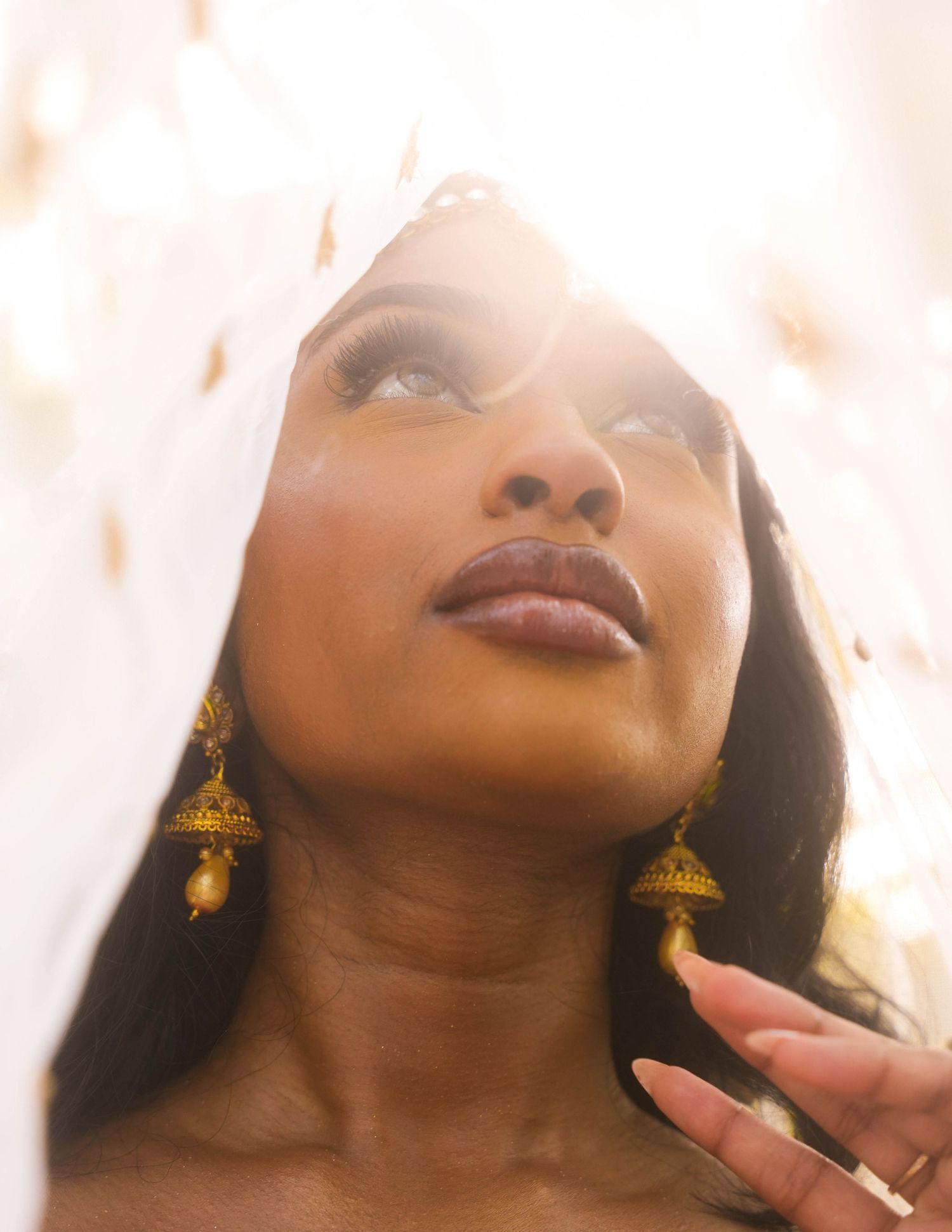 Ethereal portrait with golden earrings and soft lighting creating dreamy atmosphere.