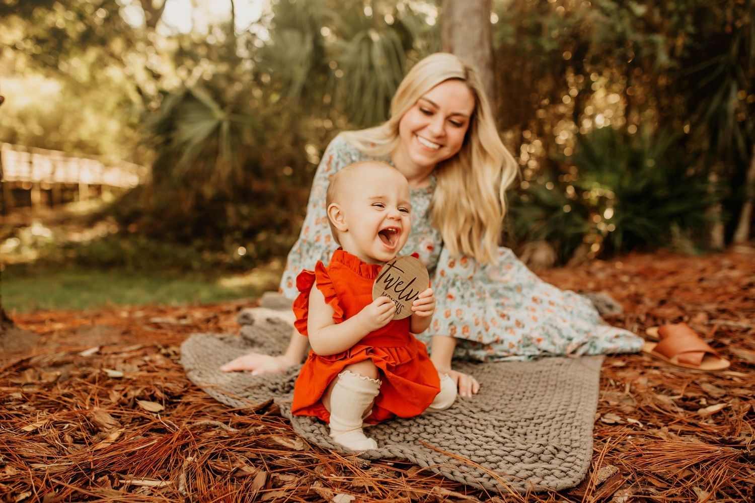 Happy moment captured on fallen autumn leaves with baby in bright red outfit.