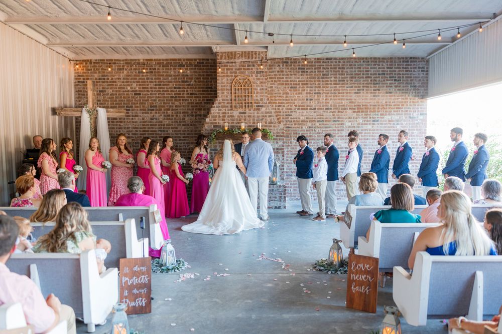 A panoramic view of a wedding ceremony setup in an industrial-style venue with exposed brick walls and white chairs.