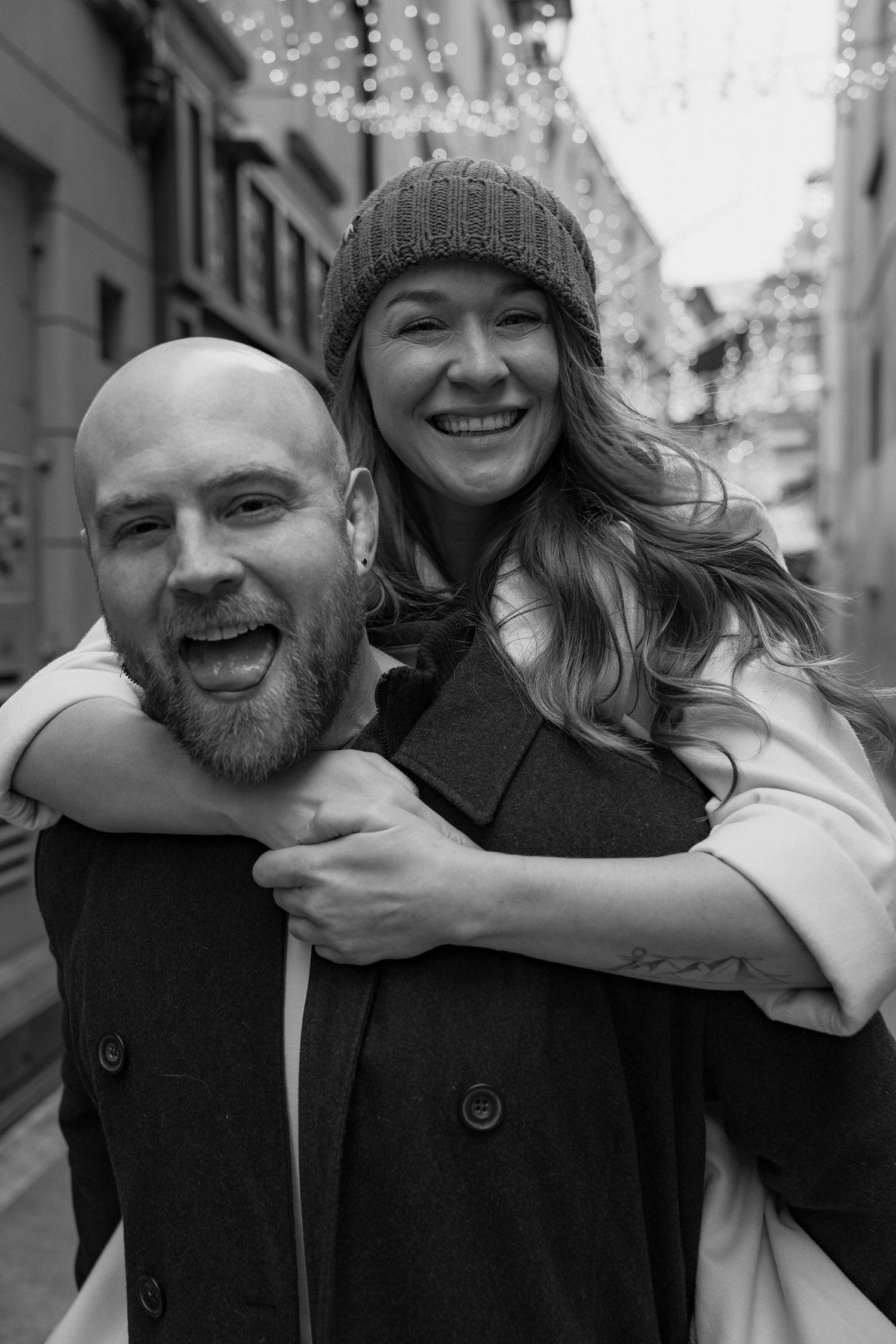Candid black and white photo of couple sharing joyful laughter and embrace on city street.