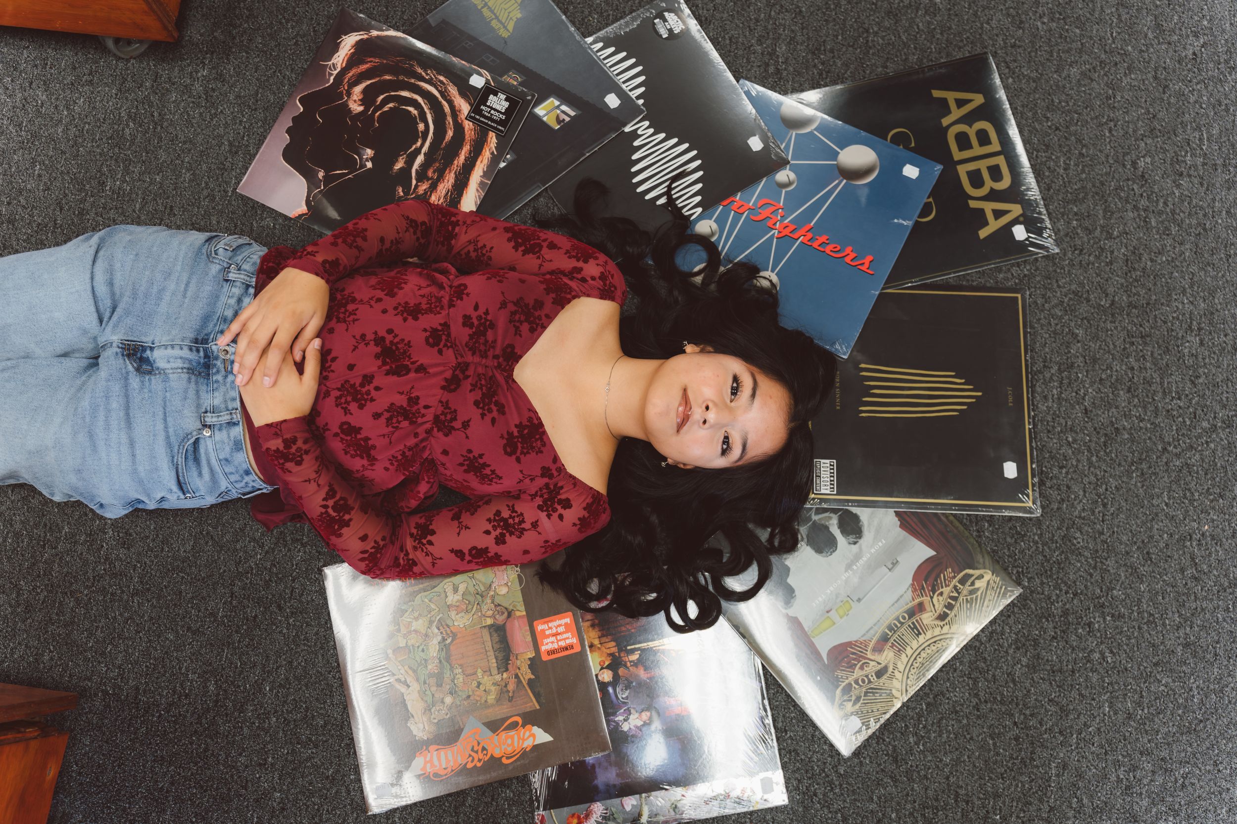 Collection of vinyl records and album covers spread out on a gray carpet floor.