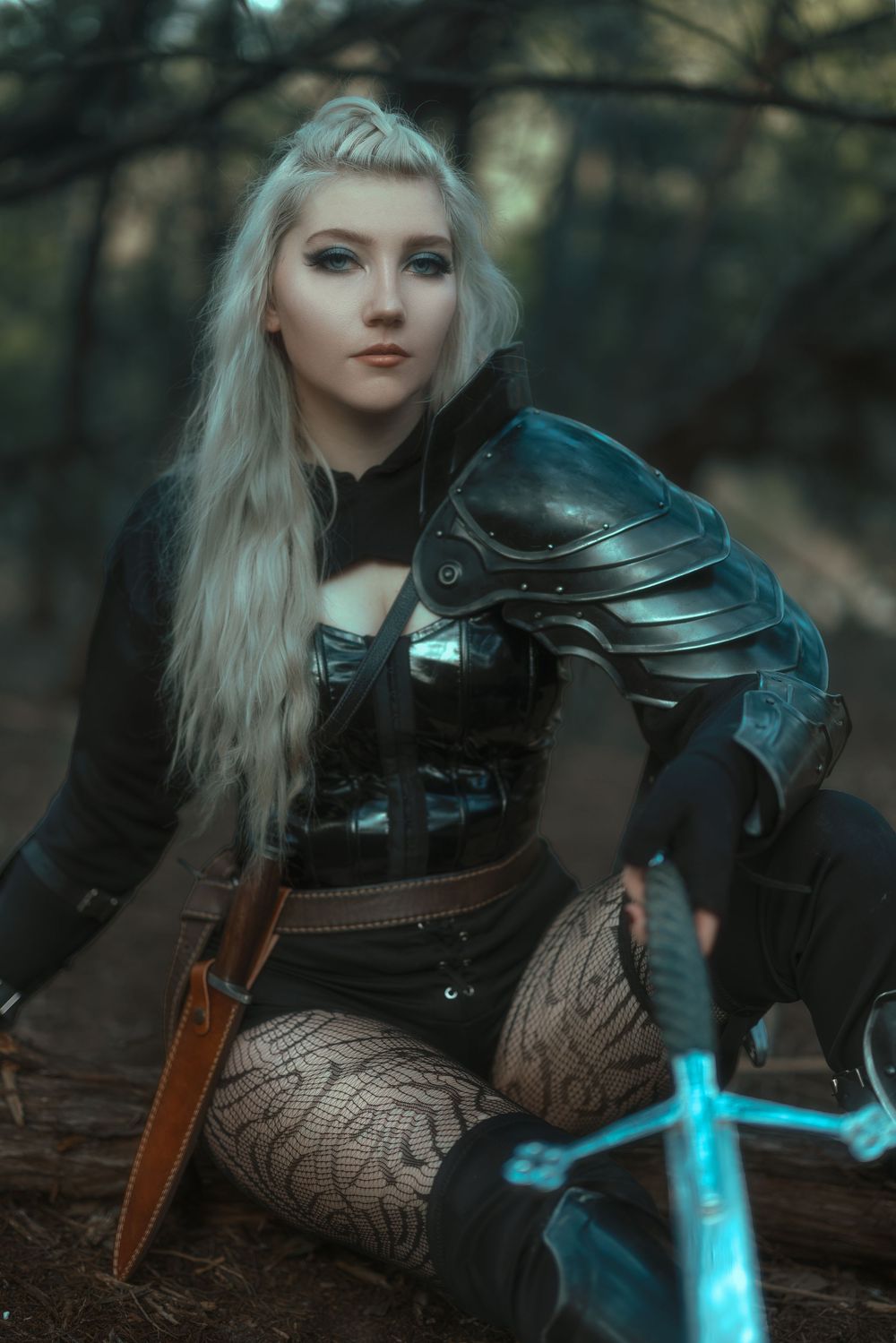 Fantasy warrior costume with glowing blue sword in atmospheric forest scene.