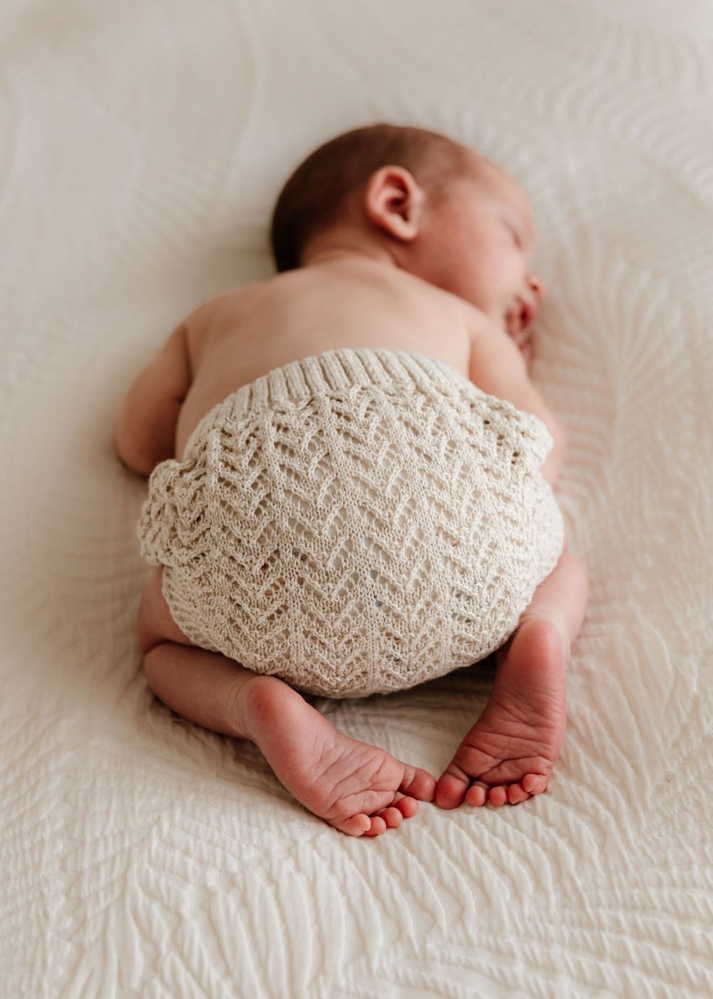 Portrait on baby sleeping on soft neutral fabric at-home during an natural lifestyle newborn photoshoot