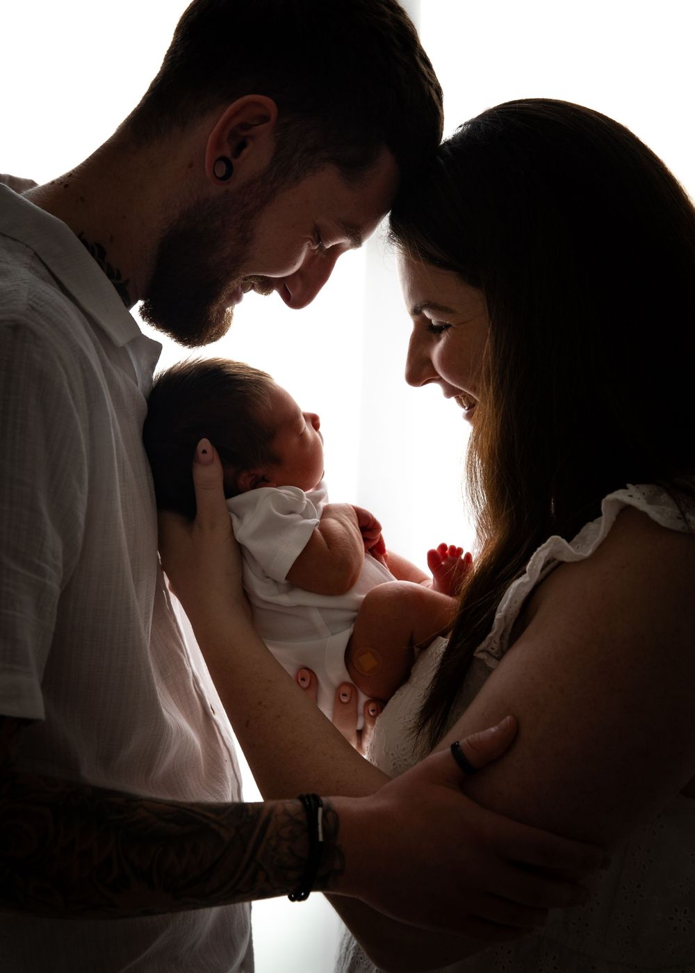Silhouette shot of parents and newborn baby backlit with white light to create an artistic family newborn portrait at-home in Dubai