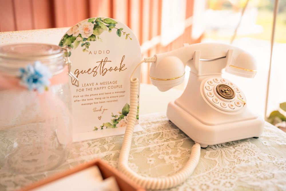 Vintage styled pink and white wedding decor with retro telephone and floral accents.