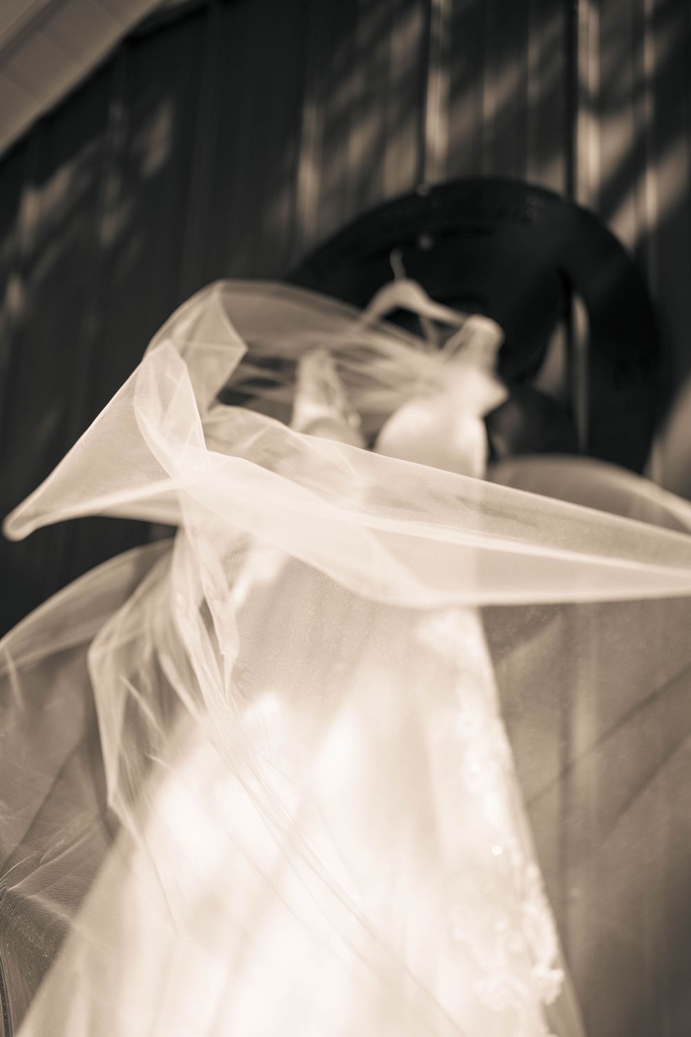 Close-up details of flowing white wedding dress fabric in dramatic lighting.