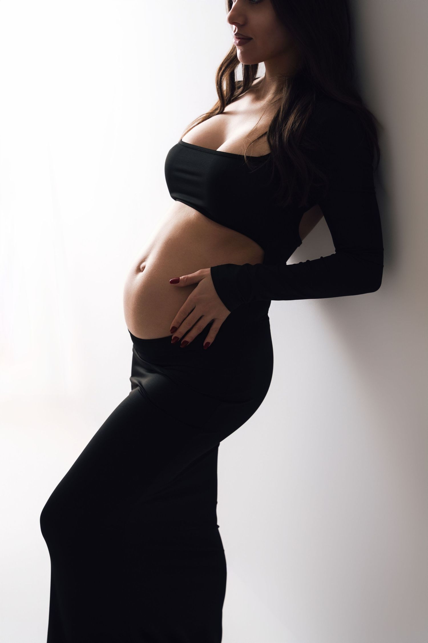Artistic maternity photos showing pregnant woman in black dress against white background.