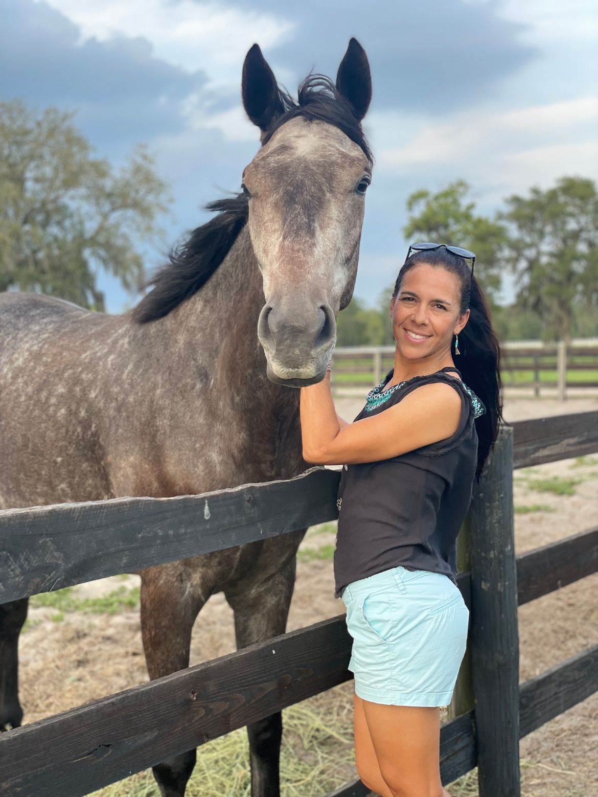 A roan horse standing behind a wooden fence in a pasture. Anita Bejarano.