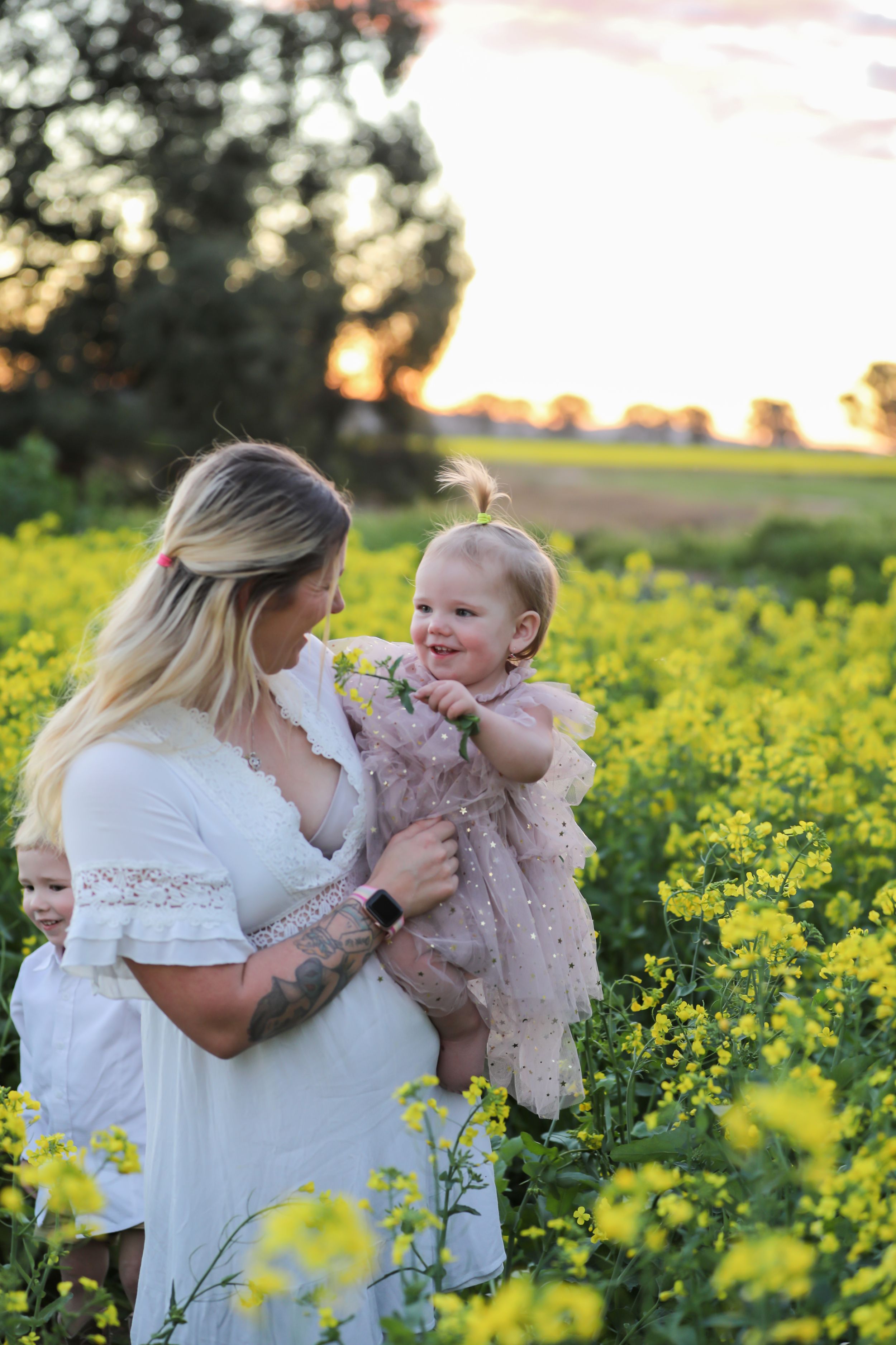 Family bonding moment in a vibrant yellow canola field at sunset.