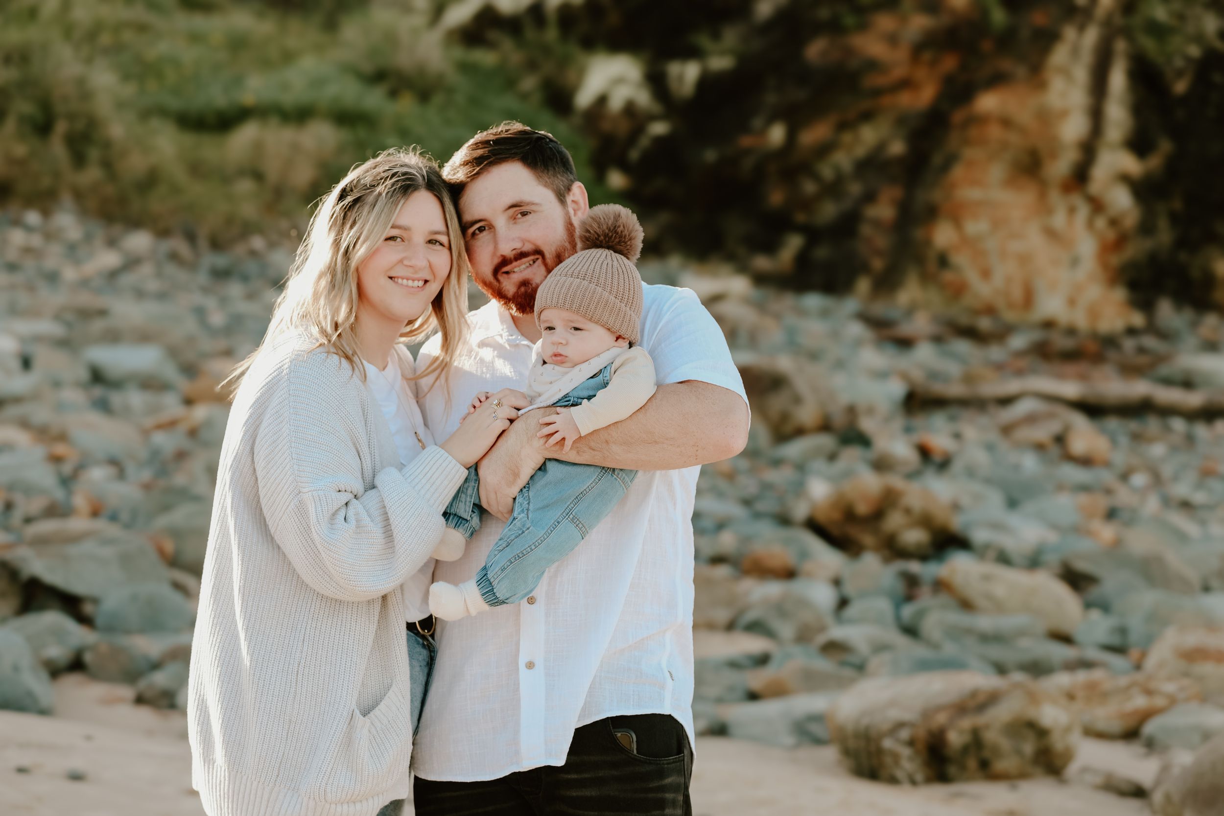 Intimate family portraits taken against rocky coastal backdrop.