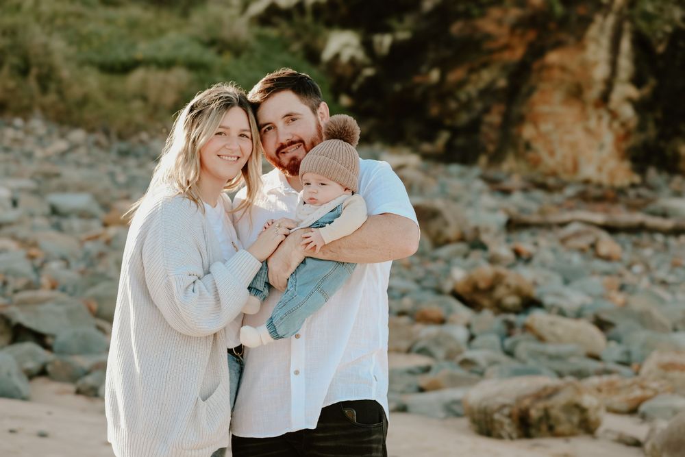 Intimate family portraits taken against rocky coastal backdrop.